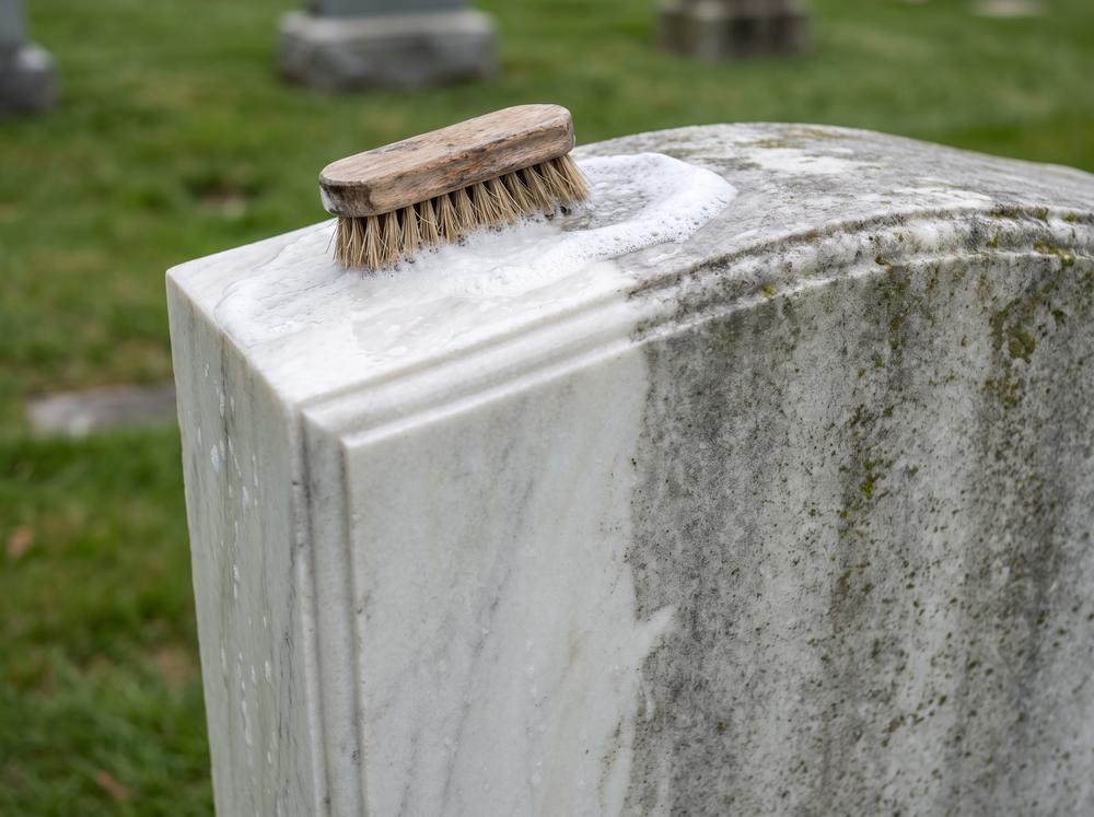 Marble headstone being gently cleaned, half restored to bright white