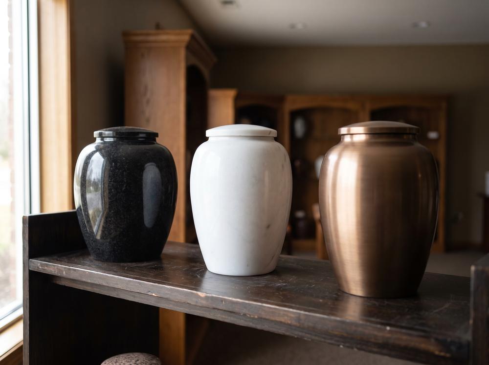 Granite, marble, and bronze cremation urns on a showroom shelf